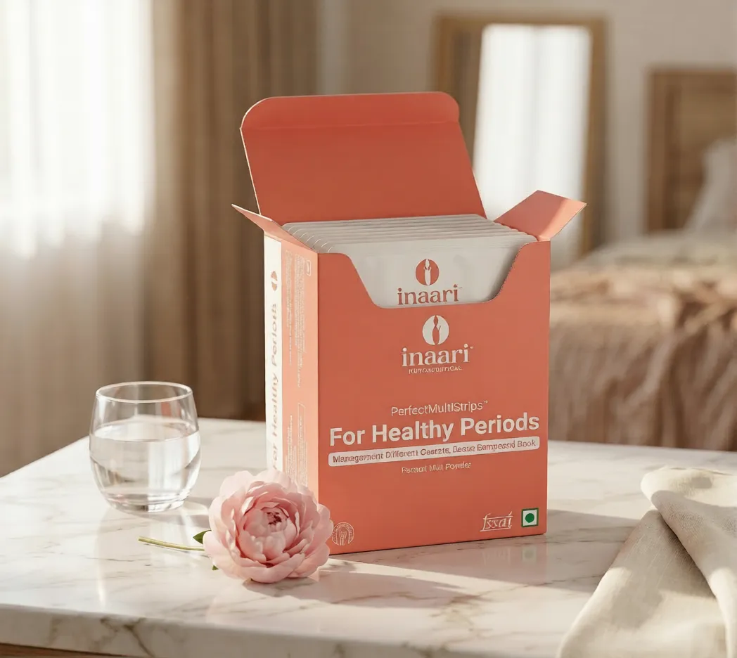 Orange Inaari box opened on a marble table with pads, a glass of water, and a pink peony in a softly lit room (period care product).