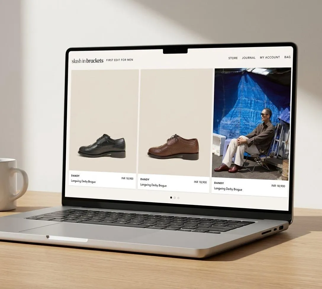 Laptop on desk showing an online shop with three product cards: two dress shoes and a man sitting in a blue tented area, webpage header visible.