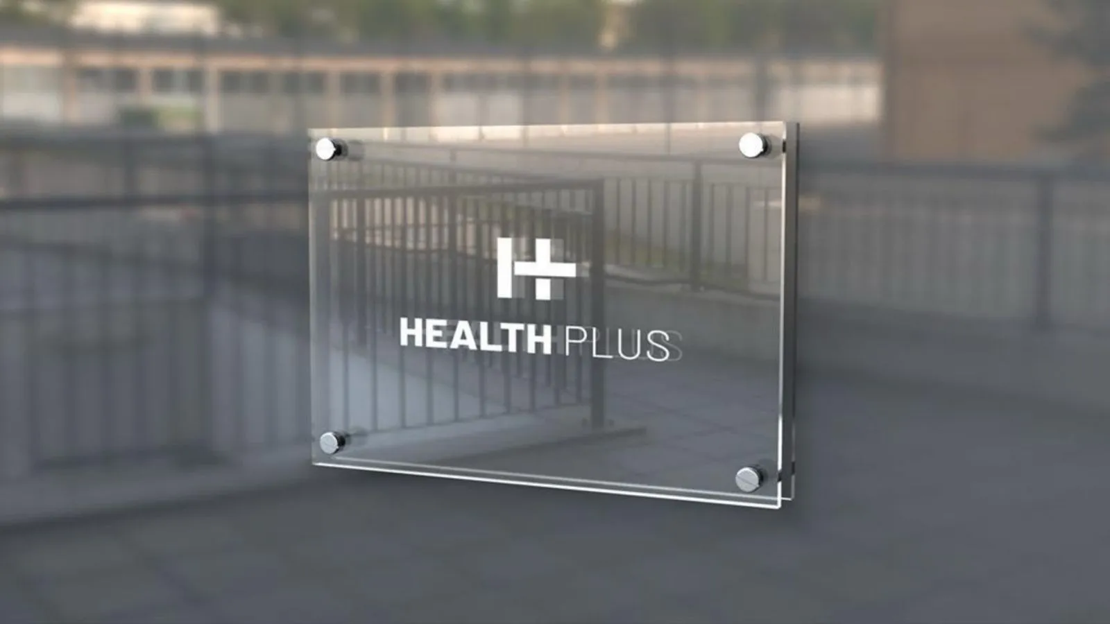 Glass wall sign displaying the Health Plus logo, mounted with metal standoffs on an outdoor railing backdrop.