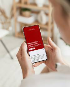 Close-up of hands holding a smartphone with a red screen and white text, user reading the content.